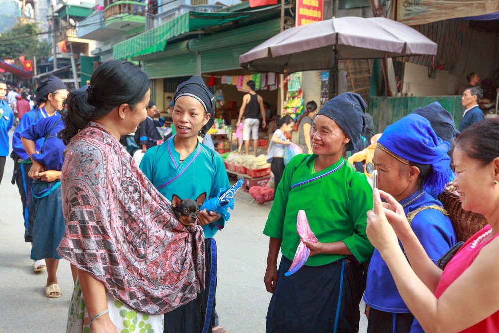 women in at market one carrying a chihuahua in her shawl