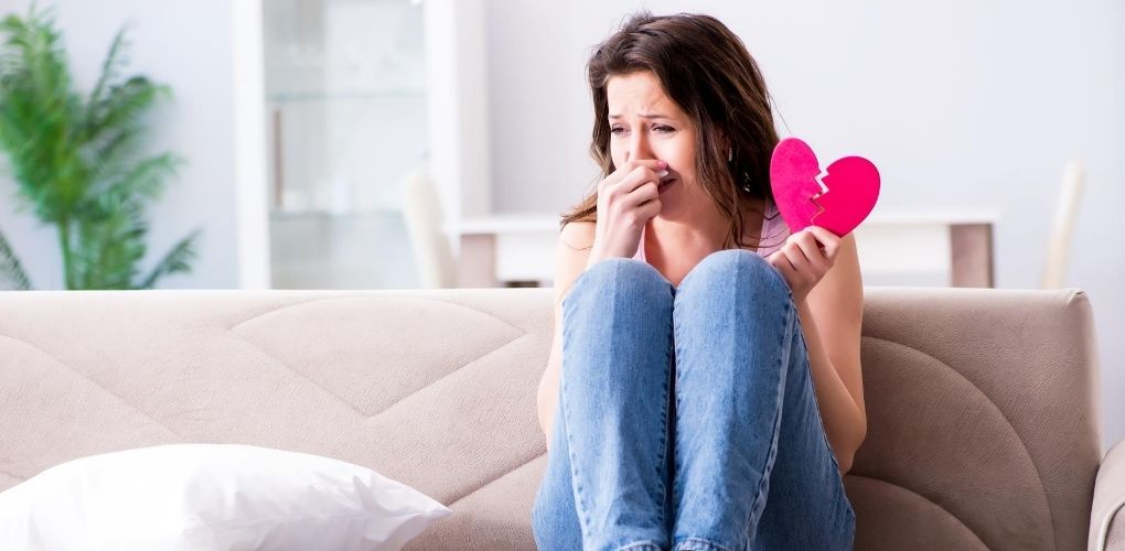 woman on couch holding a cut out paper broken heart, loss of a beloved Chihuahua